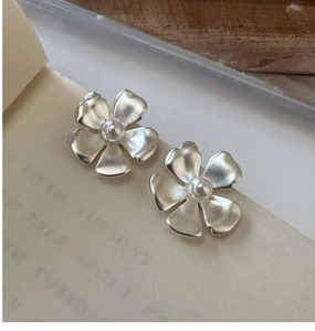 Detail of matte silver flower earring with pearl center and S925 hallmark on wood