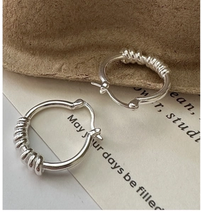 Détail macro de boucles d'oreilles S925 en argent avec texture spirale et finition polie
