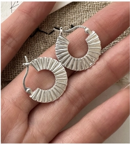 Close-up of pleated S925 sterling silver hoop earring showing detailed radial texture