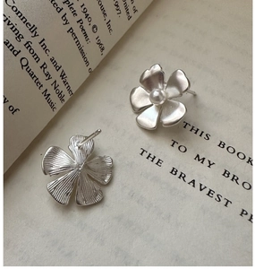 Macro view of silver floral stud earrings with matte finish and center pearl