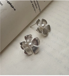 Detail of matte silver flower earrings with white pearls on a vintage book page