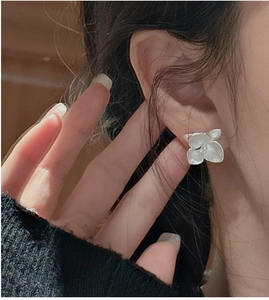 Close-up of S925 sterling silver flower earrings with matte texture on a female model