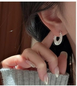 Close-up of S925 sterling silver hoop earring with pleated texture on a model's ear