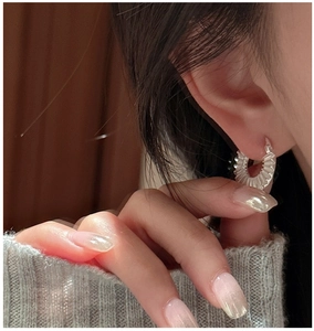 Close-up of S925 silver pleated hoop earrings worn by a model in lifestyle setting