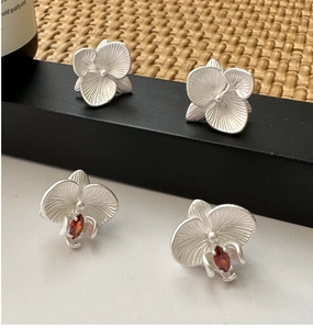 Detailed macro view of S925 silver orchid earrings with matte finish and red gemstone inlay
