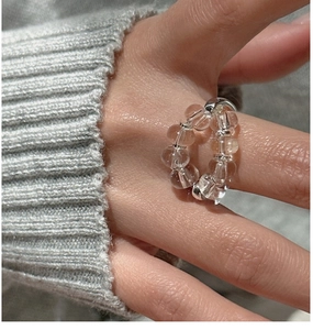 Macro shot of S925 sterling silver beaded ring with white crystal on grey knit