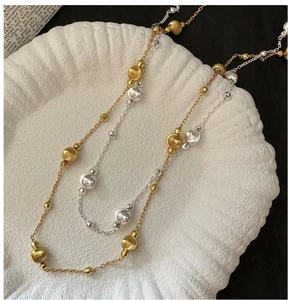 Detail of silver and gold beaded necklaces on shell tray with minimalist aesthetic