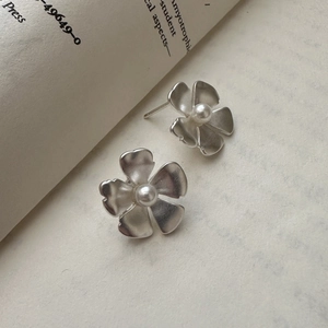 S925 sterling silver matte flower earrings with pearl centers on a vintage book background