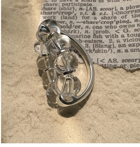 Macro detail of silver ring with five clear beads on vintage newspaper background