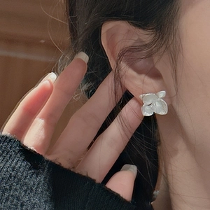 Minimalist S925 sterling silver matte flower earrings shown on a model side view