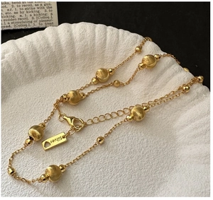 Detail of S925 silver gold bracelet with brushed beads and heart charm on a shell tray