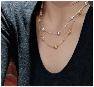 Close-up of layered S925 silver necklace with gold and silver beaded chain design