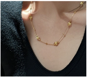 Detail of gold beaded necklace with spiral beads on black knit fabric