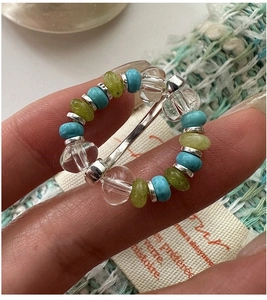 Macro detail of elastic beaded ring featuring sky blue and lemon green beads with silver spacers