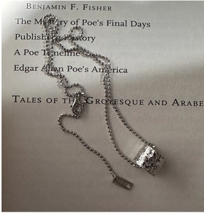 Détail du pendentif cube en argent sterling S925 avec texture martelée sur un livre