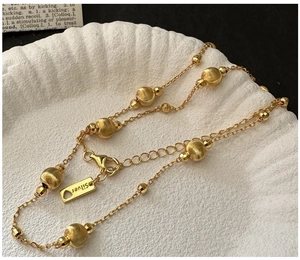 Detailed macro of S925 silver beaded gold necklace with lobster clasp on shell tray