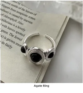 Macro shot of an adjustable silver ring with three black onyx stones on vintage book pages