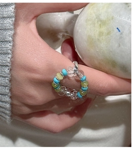 Close-up of S925 silver beaded elastic ring with blue and green beads on model finger