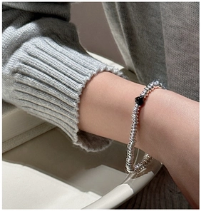 Macro shot of S925 silver beaded abacus bracelet with a single black bead on wrist