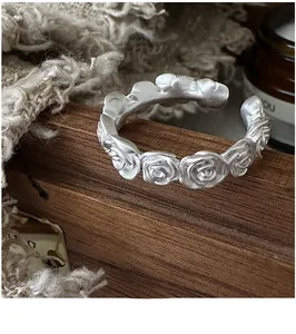 Detailed close-up of a vintage matte silver rose ring with a 3D floral relief pattern