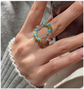 Detailed close-up of elastic beaded ring with blue, green, and clear silver-spaced beads