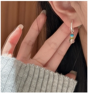 Detail of silver drop earrings with colorful beads worn by a model in close-up