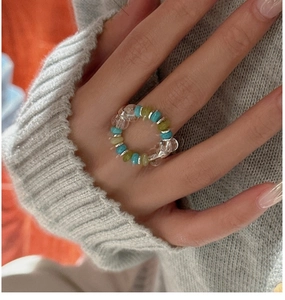 Detail of beaded elastic ring with green and turquoise beads on a model's finger