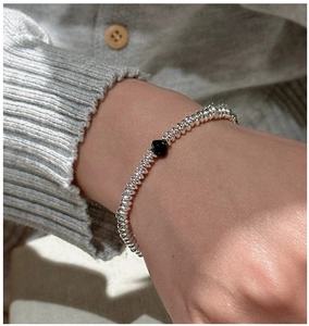Detailed view of an S925 silver beaded bracelet with a black bead on a woman wrist