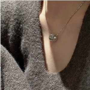 Détail du collier pendentif en argent sterling S925 sur un pull en maille grise