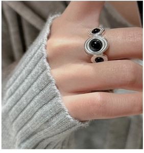 Macro detail of retro S925 silver ring with three black onyx stones on knitted background