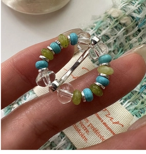 Detailed shot of bohemian beaded ring with blue and green stones on an elastic band