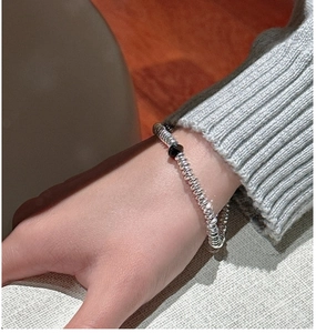 Macro detail of the beaded silver bracelet featuring flat metal disks and a black center bead