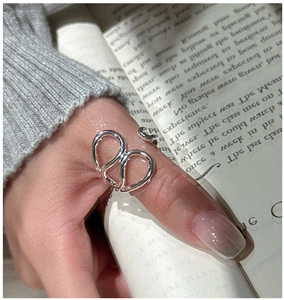 Detailed view of layered S925 sterling silver twist ring worn by a model over a book