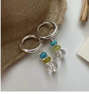 Detail of silver hoop earrings featuring turquoise, green, and clear crystal beads