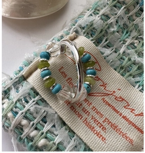 Macro detail of S925 silver beaded elastic ring with turquoise and green stones