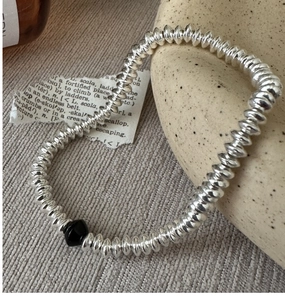 Detailed shot of silver beaded bracelet with black faceted bead on knit background
