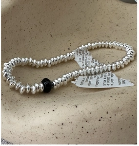 Detail of vintage S925 silver beaded bracelet with black focal bead on ceramic plate