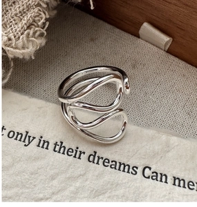 Close-up of S925 sterling silver multi-layer wavy ring on vintage linen and paper