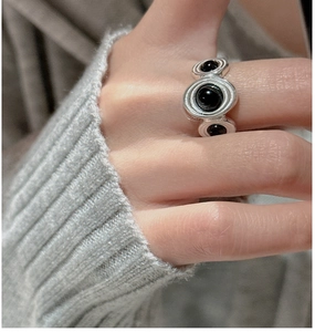 Detail of silver S925 ring with three black onyx stones on a grey knit background