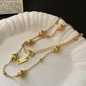 Elegant gold S925 silver beaded necklace displayed on a white shell tray with vintage book