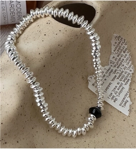 Detail of S925 silver beaded abacus bracelet with black bead on a ceramic dish