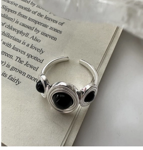 Macro shot of silver ring with three black onyx stones on a book page with crystal