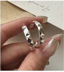 Gros plan de boucles d'oreilles créoles en argent S925 avec textures CNC géométriques