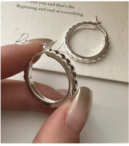 Detailed close-up of S925 sterling silver hoop earrings with wavy gear edge design