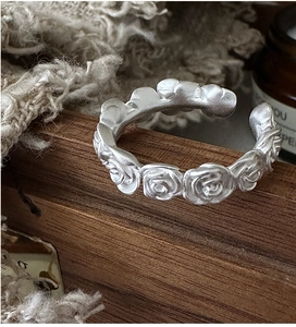 Close-up of S925 sterling silver rose ring with vintage matte texture on dark wood background