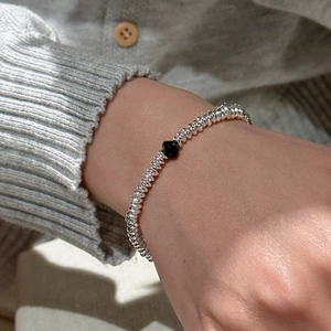 Minimalist S925 sterling silver beaded bracelet with a black heart pendant on a model