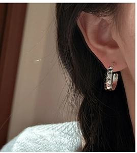 Gros plan détaillé des boucles d'oreilles C-hoop en argent S925 avec texture pyramide CNC