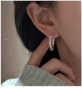 Close-up of S925 sterling silver hoop earrings with unique geometric gear-like texture