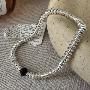 Minimalist S925 silver beaded bracelet with black geometric charm on a beige fabric