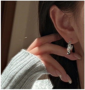 Gros plan d'une créole en argent S925 avec texture de prisme géométrique portée à l'oreille